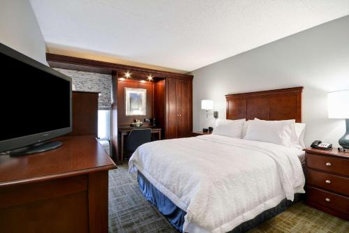 a hotel room with a bed and a flat screen tv at Hampton Inn Detroit Northville in Northville