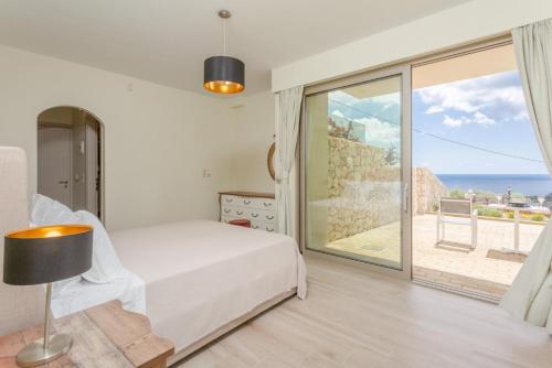 Villa Lassi Illios في كيفالونيا: غرفة نوم مع سرير وإطلالة على المحيط