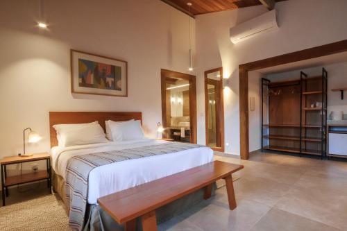 a bedroom with a large bed and a wooden bench at Pouso Alforria in Tiradentes