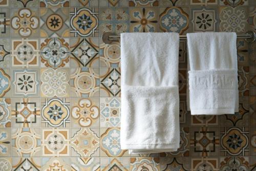 two white towels hanging on a wall with tiles at Villa Lassi Fos in Kefallonia