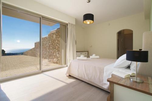a bedroom with a bed and a large window at Villa Lassi Fos in Kefallonia