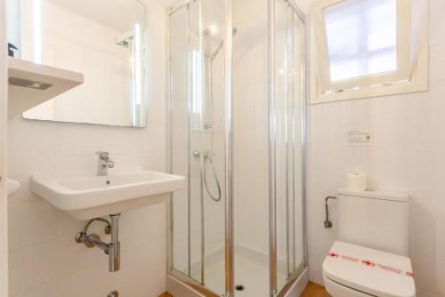 een badkamer met een douche, een wastafel en een toilet bij Villa Binibety in Binibeca