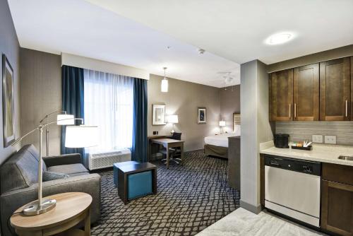 a hotel room with a bed and a living room at Homewood Suites By Hilton Warren Detroit in Warren