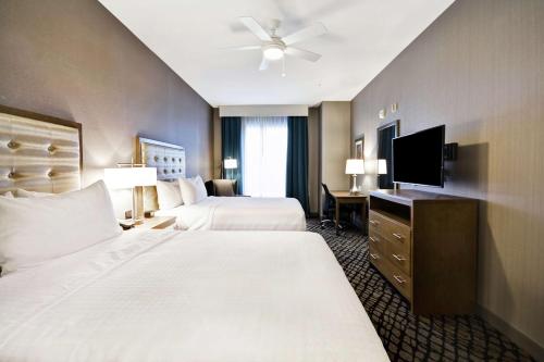 a hotel room with two beds and a flat screen tv at Homewood Suites By Hilton Warren Detroit in Warren