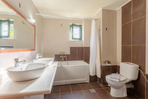 uma casa de banho com um lavatório, uma banheira e um WC. em Villa Dimitrios em Vlikhádha