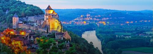 a castle on the side of a hill with a river at LES TROIS L in Gindou