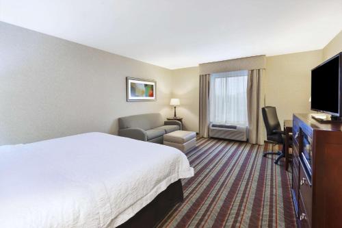 a hotel room with a bed and a flat screen tv at Hampton Inn Detroit/Southgate in Southgate