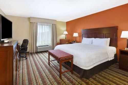 a hotel room with a bed and a flat screen tv at Hampton Inn Detroit/Southgate in Southgate
