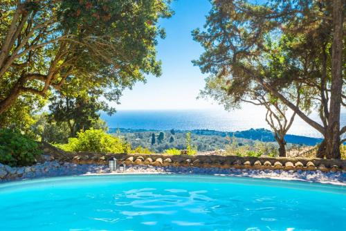 uma piscina com árvores e o oceano ao fundo em Villa Nionios em Vlachopoulátika