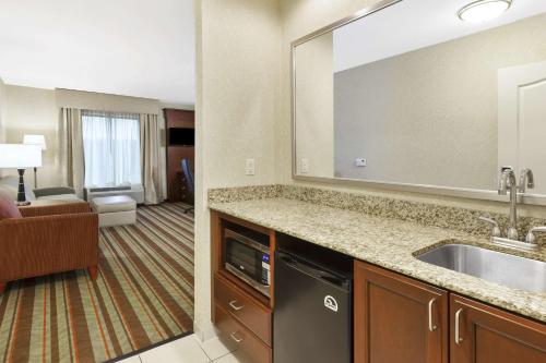 Habitación de hotel con lavabo y sala de estar. en Hampton Inn Detroit/Southgate en Southgate