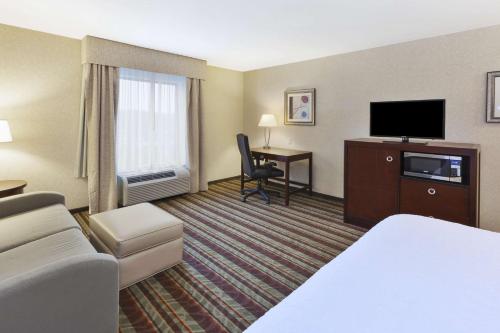 a hotel room with a bed a desk and a television at Hampton Inn Detroit/Southgate in Southgate