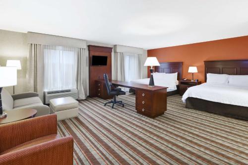 サウスゲイトにあるHampton Inn Detroit/Southgateの大きなベッドとデスクが備わるホテルルームです。