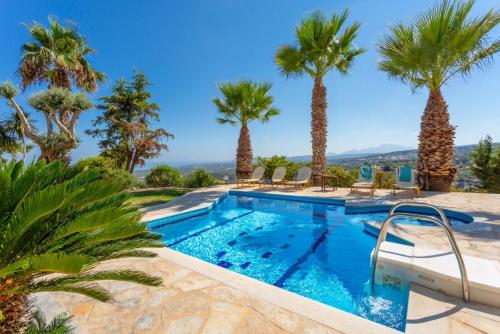 una piscina con palmeras en un complejo en Villa Astro, en Agia Triada