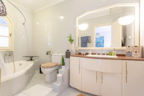 a white bathroom with a tub and a toilet and a sink at Villa Durrell in Kontokali