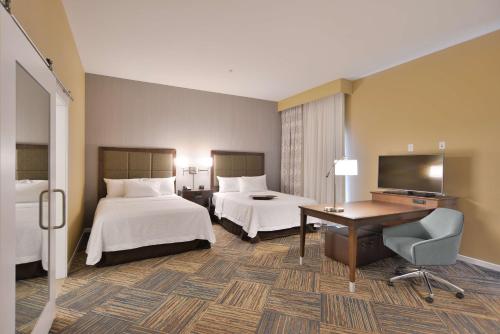 a hotel room with two beds and a desk and a television at Hampton Inn & Suites Chippewa Falls in Chippewa Falls