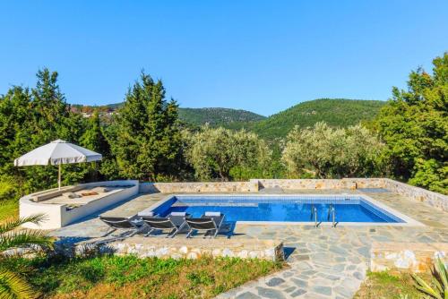 una piscina con sillas y sombrilla en Villa Levanda, en Panormos Skopelos
