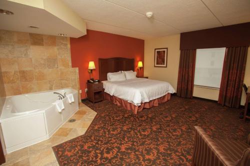 a hotel room with a bed and a bath tub at Hampton Inn Elmira/Horseheads in Horseheads