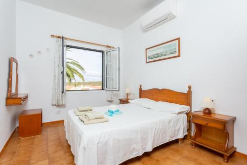 a bedroom with a white bed and a window at Villa Bini Estrella in Es Canutells
