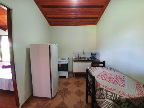 a kitchen with a refrigerator in the corner of a room at Chalé e Camping Elementais in São Thomé das Letras