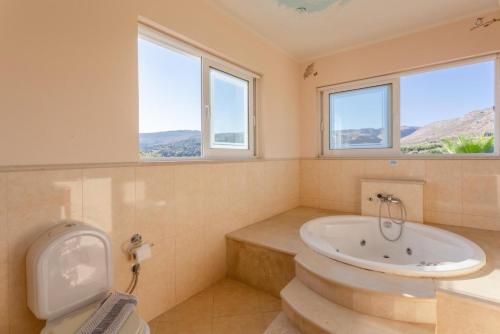 a bathroom with a tub and a toilet and windows at Villa Pelagos in Agia Triada