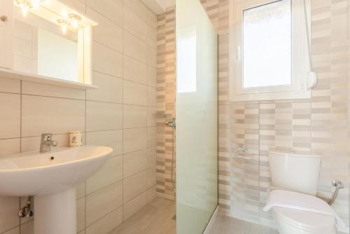 a white bathroom with a sink and a toilet at Vatsa Beach Villa in Kounopetra