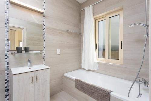 ein Bad mit einer Badewanne, einem Waschbecken und einer Dusche in der Unterkunft Villa Christel in Lachi