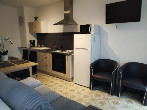 uma cozinha com um frigorífico branco e 2 cadeiras em Maison em Damblain