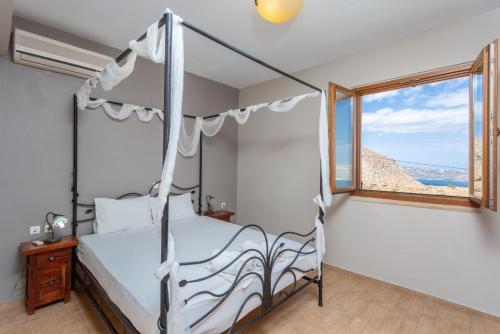 1 dormitorio con cama con dosel y ventana en Villa Stratos, en Zakhariás