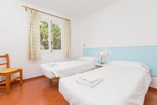 a room with two beds and a chair and a window at Villa Trepuco Uno in Punta Prima