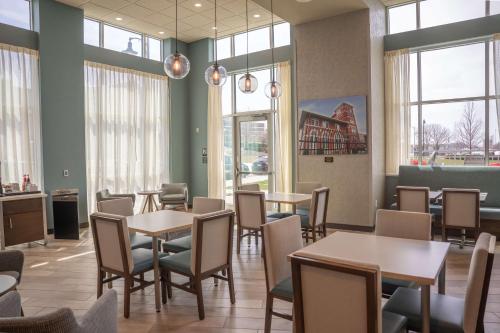 a dining room with tables and chairs and windows at Hampton Inn & Suites Erie Bayfront in Erie