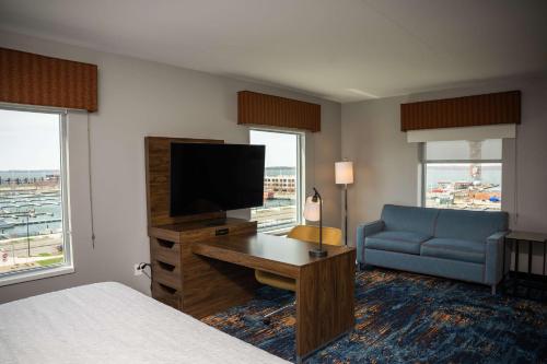 a hotel room with a bed and a television and a couch at Hampton Inn & Suites Erie Bayfront in Erie