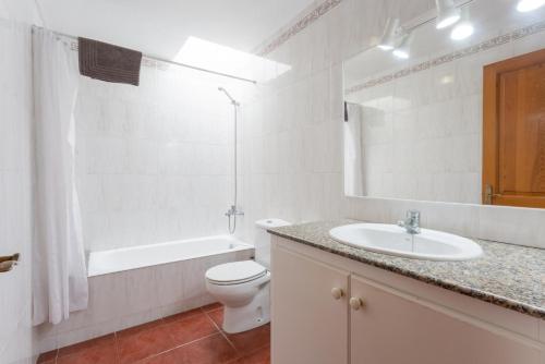 a white bathroom with a sink and a toilet and a tub at Villa Calitja Dos in Cala'n Bosch