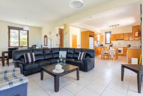 a living room with a black couch and a kitchen at Villa Halima Georgios in Polis Chrysochous