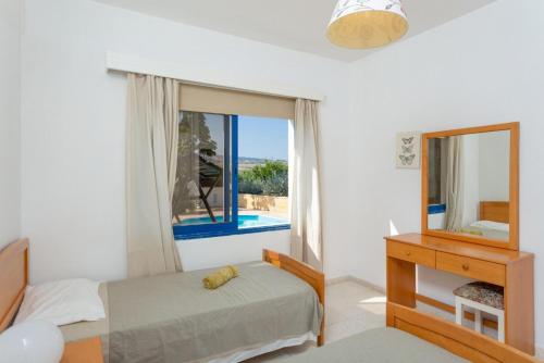 a bedroom with a bed and a mirror and a window at Villa Charoula Tria in Paphos City