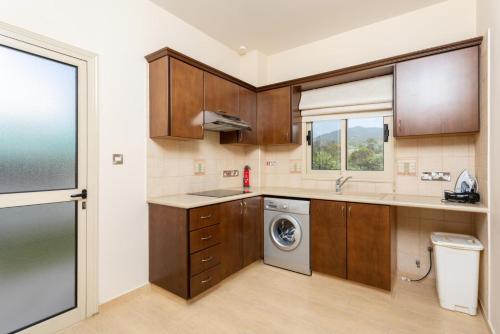 a kitchen with wooden cabinets and a washing machine at Villa Rose in Paphos City