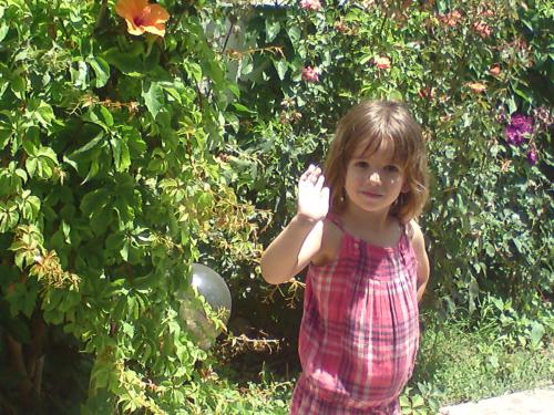 Una niña con un vestido rosa parada en un jardín en Kiveli en Milatos