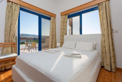 a bedroom with a large white bed and large windows at Villa Charoula Tessera in Polis Chrysochous