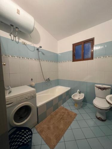 a bathroom with a toilet a sink and a washing machine at Cela House in Divjakë
