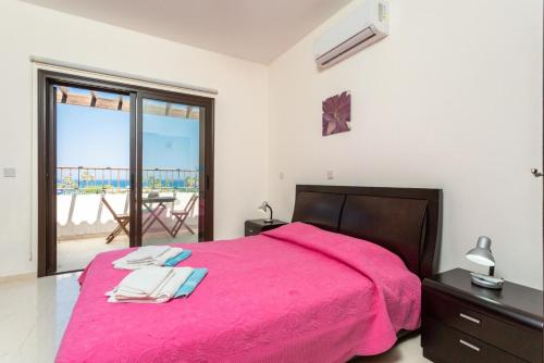 1 dormitorio con cama rosa y balcón en Villa Fortuna, en Polis Chrysochous