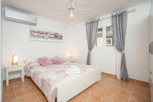a white bedroom with a bed and a window at Villa Maria in Cala en Porter