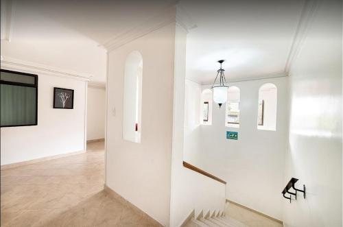 a hallway with white walls and stairs in a house at Hotel Lukas in Medellín