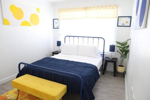 a bedroom with a blue bed and a yellow bench at Insta Worthy Modern Bungalow in Homestead
