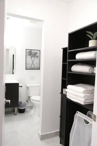 a bathroom with a toilet and a shelf with towels at Insta Worthy Modern Bungalow in Homestead