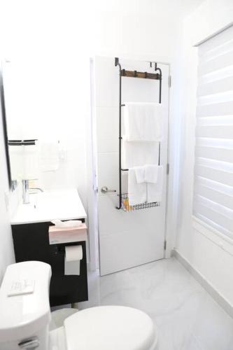a white bathroom with a toilet and a sink at Insta Worthy Modern Bungalow in Homestead