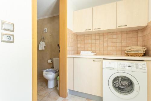 een badkamer met een wasmachine en een toilet bij Villa Fedra in Póros
