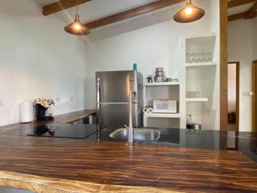 a kitchen with a stainless steel refrigerator and wooden floors at La casa del Artesano !Casa completa frente al mar! in Santa Cruz