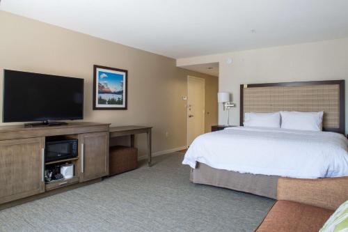 a hotel room with a bed and a flat screen tv at Hampton Inn & Suites Whitefish in Whitefish