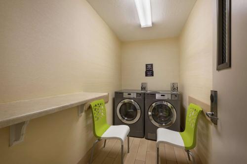 a laundry room with two green chairs and a washing machine at Hilton Garden Inn Flagstaff in Flagstaff
