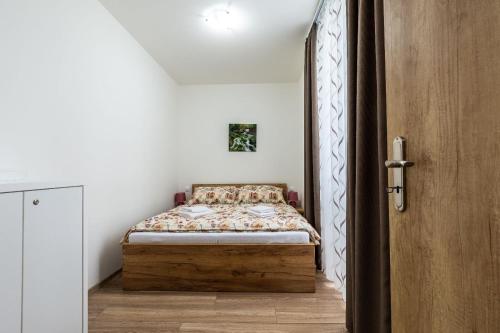 a small bedroom with a bed and a wooden door at Apartmán Janka in Liptovský Ján