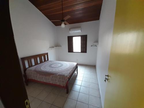 a bedroom with a bed and a window in it at Mandala casa 3 dorms cond fech piscina churrasqueira in Boicucanga